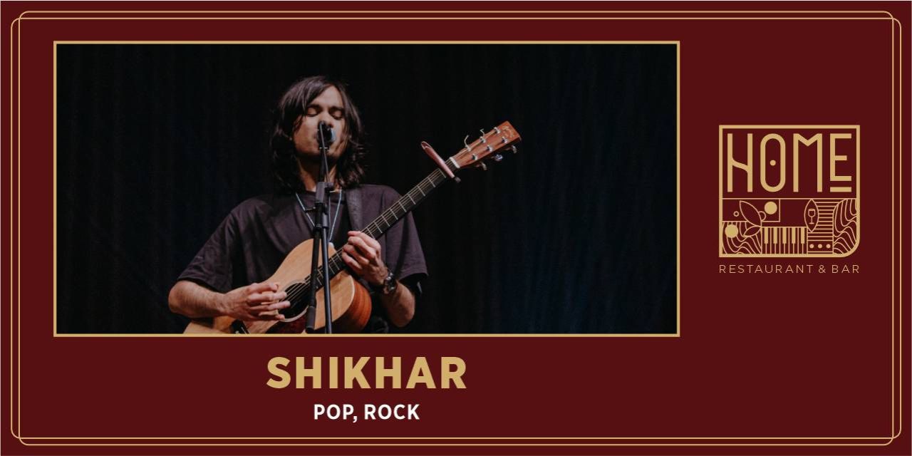 Shikhar performing live with an acoustic guitar on stage during an intimate music set