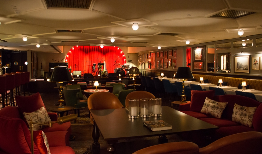 Red curtains at the hotel bar. Dim lighting and plush seating create a warm ambiance