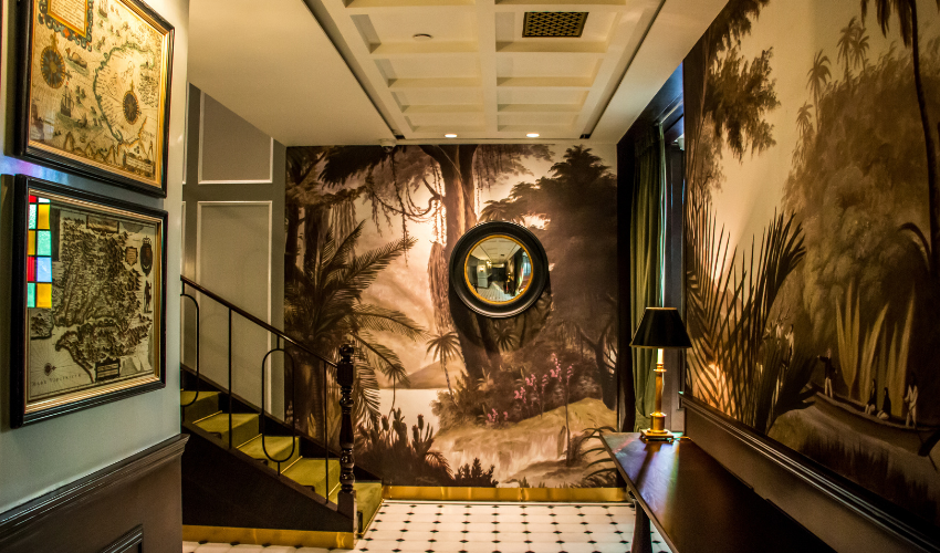 captivating hallway adorned with a beautiful painting on the wall and a grand staircase beckoning you to explore further