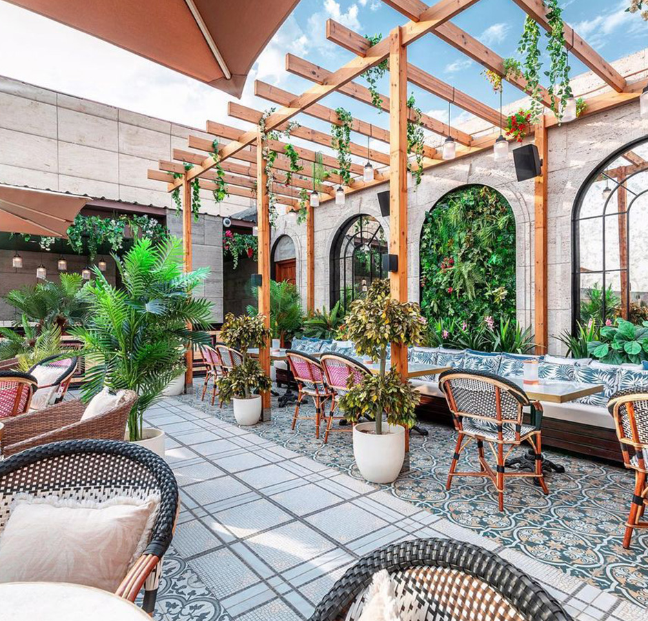 A beautifully decorated hotel patio featuring plants and stylish wicker furniture